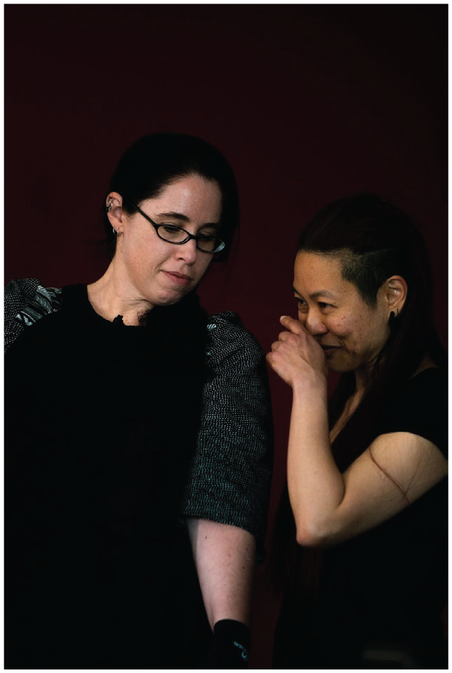 A photograph of a white woman and a woman who identifies as 'cuturally diverse', close together, with the Asian woman laughing or perhaps saying something secretively to the white woman